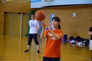 体育館内で、飛んできたバスケットボールを受け取ろうと両手を構えている女性の写真