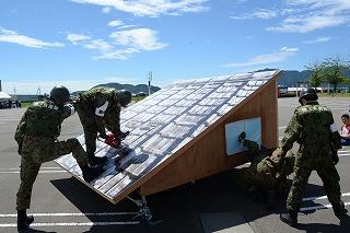 屋根の模型を囲み、障害物を動かすなどの訓練をしている隊員たちの写真