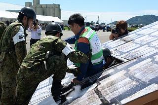 屋根の模型の中から、被災者を救出する訓練をしている隊員たちの写真