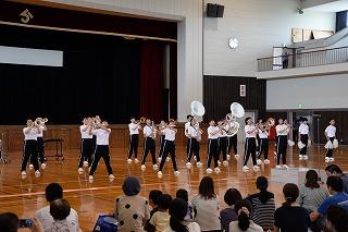白いシャツに黒いパンツをはいた中学生たちが、整列して楽器を演奏している写真