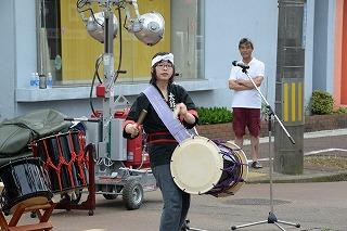 はっぴを着た女性が、和太鼓を肩からさげて演奏している写真