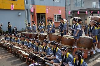 前列で座った状態、後列で立った状態で、それぞれ和太鼓を演奏する子供たちの写真