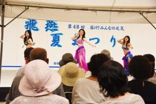 セパレートタイプのカラフルな衣装を着た三人の女性が、舞台の上で踊っている写真