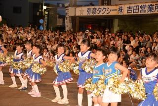 青いチアガールの服を着た子供たちが並んで踊っている写真