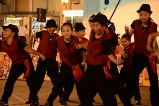 赤と黒の衣装を着た子供たちが、集まって踊っている写真