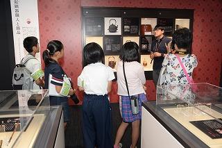 説明を受けながら史料館の展示物を見ている児童たちの写真
