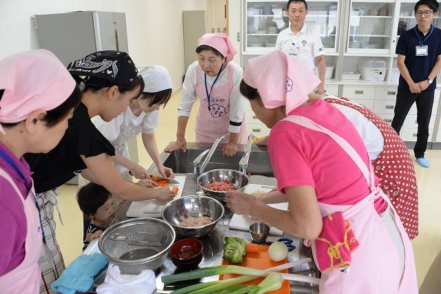 エプロンと三角巾をつけて、調理室で野菜を切っている参加者の写真