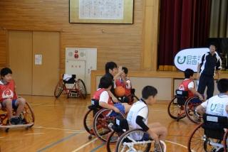 体育館内で車椅子バスケットボールに挑戦している生徒達の写真