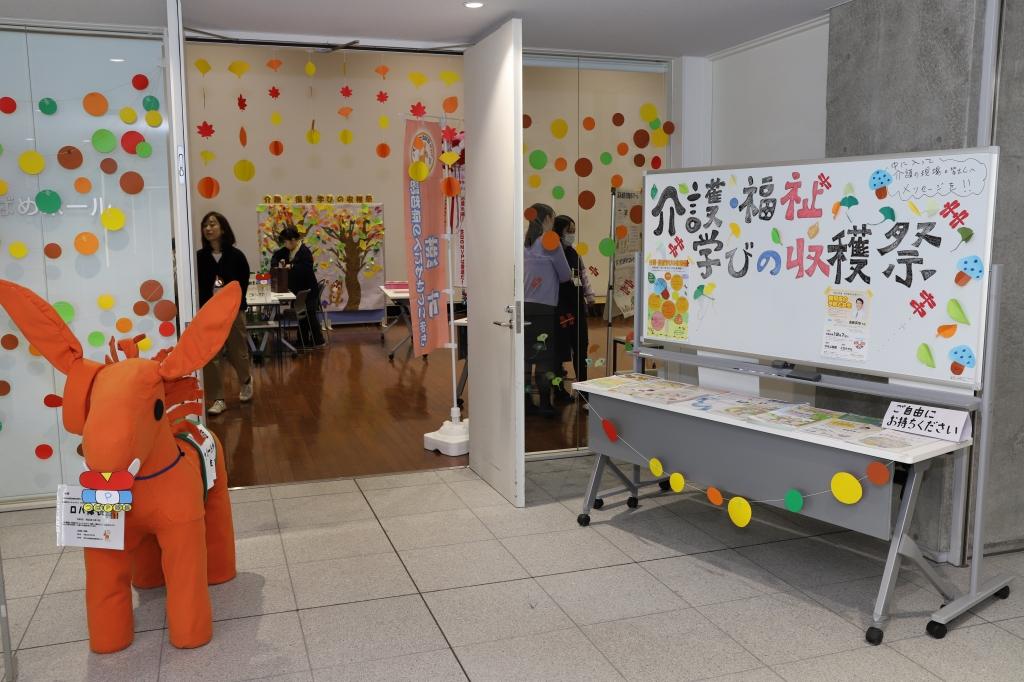 オレンジ色のキャラクターの置物が置かれたイベント会場入口の写真