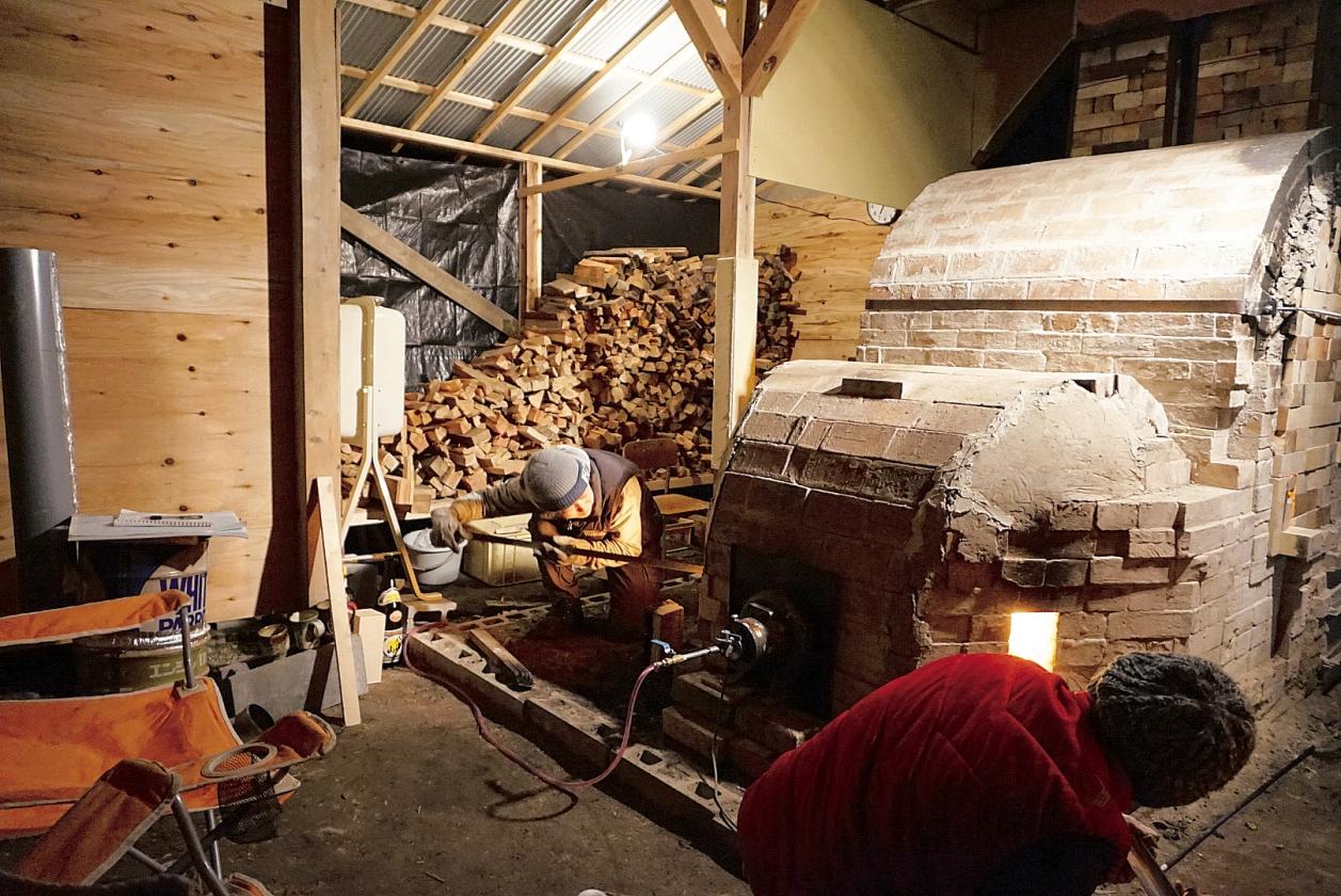 レンガを組み立てた窯と、たくさんの薪が並んでいる写真
