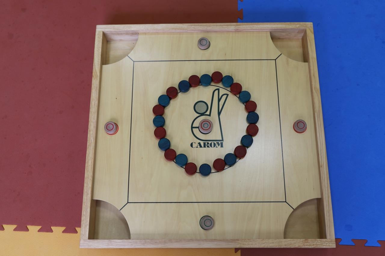 赤と青のコマが円状に並べられているボードゲームカロムの台の写真