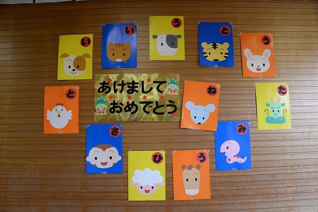 保育園の壁に「あけましておめでとう」のカードの周りに貼られた12支のキャラクターの絵のかるたの写真