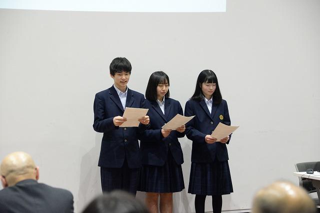 書類を手に立ち発表をしている3人の学生達の写真