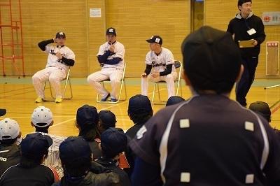 スチール椅子に座って選手3人が小学生たちに野球の話を講義している写真