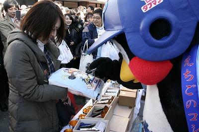 2011東京ヤクルトスワローズファン感謝Dayで袋を持ち差し出す女性につば九郎の着ぐるみを着て、その袋にサインをしている写真