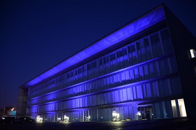 深い青色のライトで壁一面が照らされた市役所の外観写真