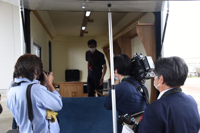 トレーラーの内部を撮影している報道陣と、内部を見て回っている人の写真
