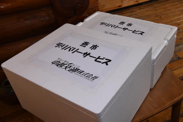 「燕市 デリバリーサービス」の紙が貼られた白い発泡スチロールの箱が二つ並んでいる写真