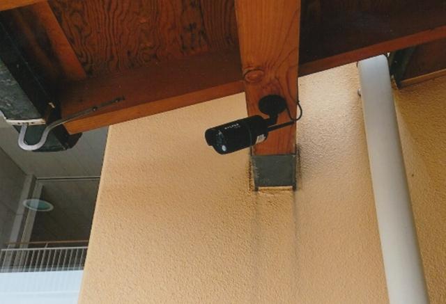 木造の建物の梁の部分に、黒い防犯カメラが取り付けられている写真
