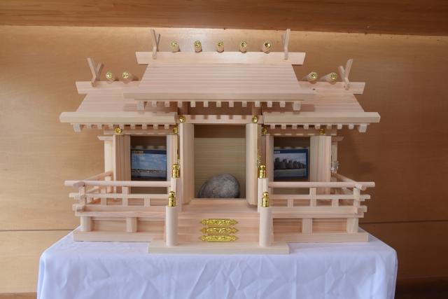 白木造りの小型の神社と、その中にご本尊として鎮座する川底の石の写真