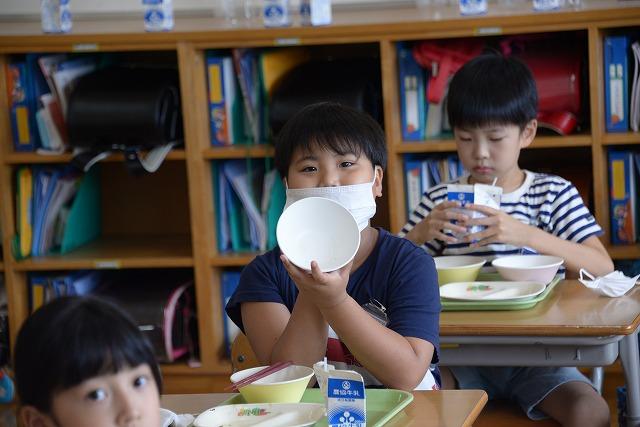 食べ終えた後の空いたお皿をこちらにかかげてにっこり微笑む生徒の写真