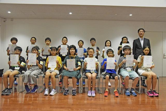 賞状を持って記念撮影する笑顔の小学生たちの写真