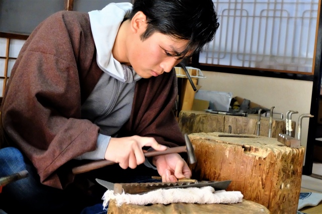 金属板を金槌で叩いて丸める岩浪さん