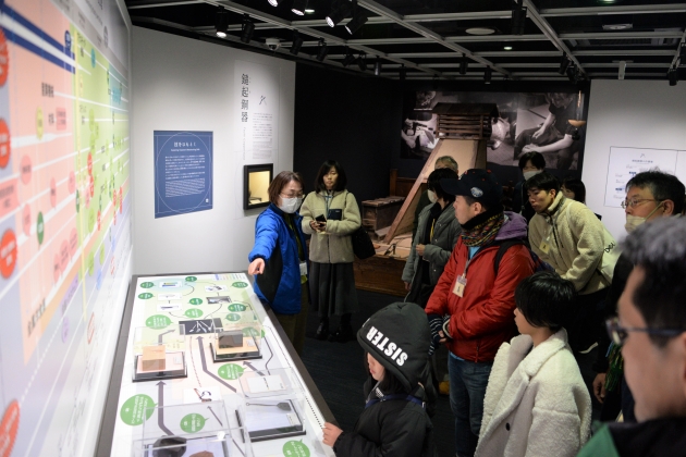 産業史料館スタッフによる館内ガイドを聞きながら展示を眺める参加者の皆さん